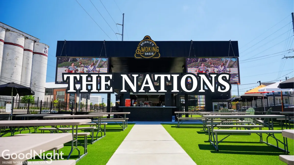 An outdoor dining area with tables and a barbecue smokehouse structure, framed by a large sign reading 'THE NATIONS.' The atmosphere is festive, with hints of live music and group gatherings, capturing the spirit of local culture and group camaraderie.