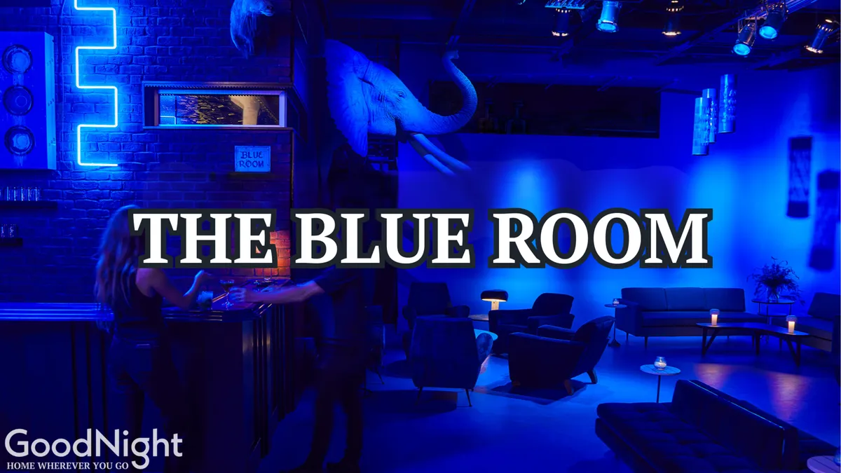 An upscale lounge interior decked in neon blue lighting, featuring a mounted elephant head, plush lounge seating, and a sleek bar area. The mood is sophisticated yet chill, evoking the feel of trendy lounges and stylish spots for nightcaps after a night out.