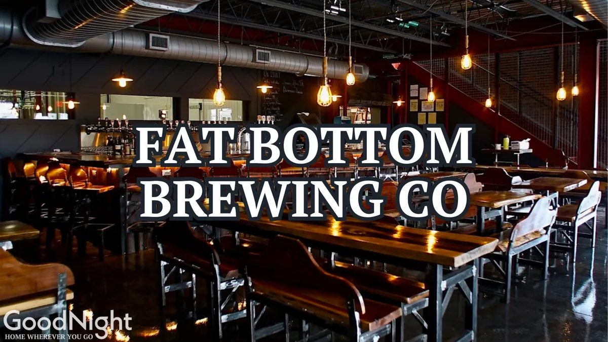 An interior view of a relaxed brewery or bar features long communal wooden tables, industrial lighting, and a visible bar area. The space is filled with an inviting, communal energy and is ideal for craft beer tastings or casual dining with friends.