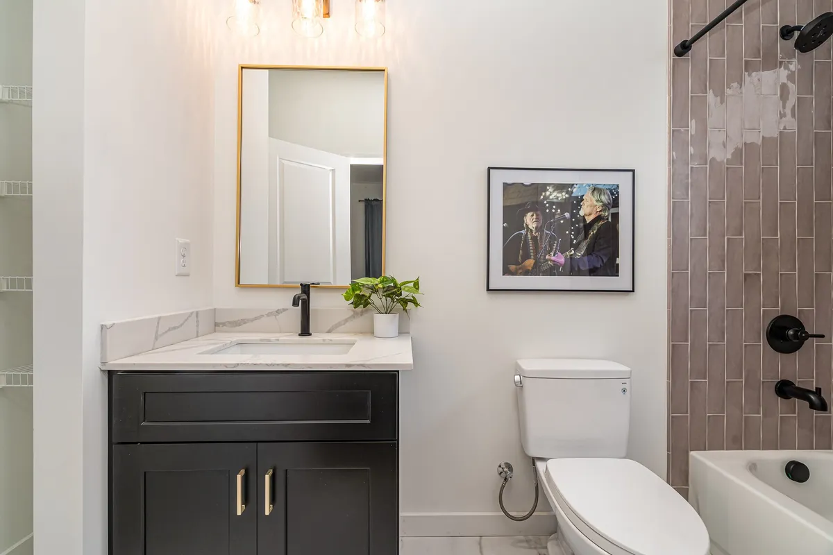A sleek bathroom vanity with a sink, framed artwork, a mirror, and a touch of greenery. The space feels tranquil and up-to-date, ideal for refreshing routines or self-care moments.