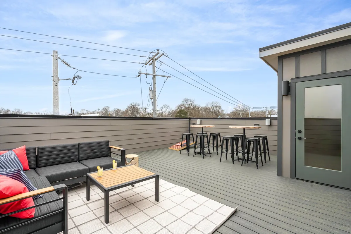 An inviting exterior patio with a table and stools, an outdoor rug, and seating designed for small gatherings under the stars. The space is casual and comfortable, ideal for evening get-togethers and enjoying the city lights after exploring Nashville.